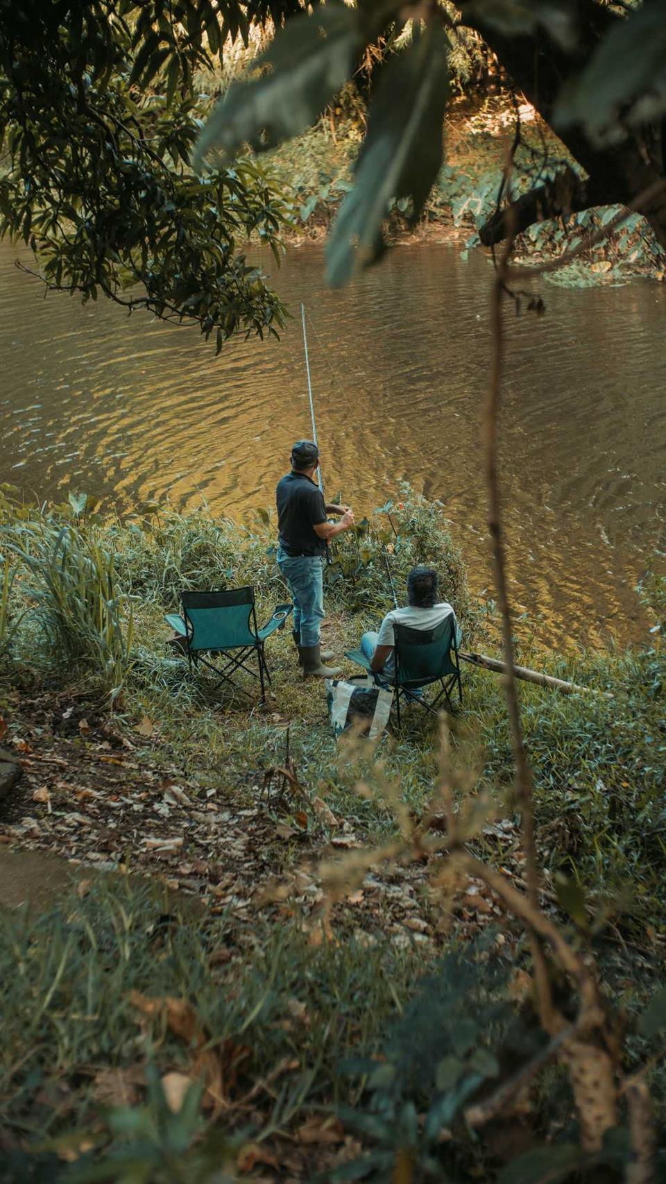 Descripción: Dos hombres pescando junto a un río